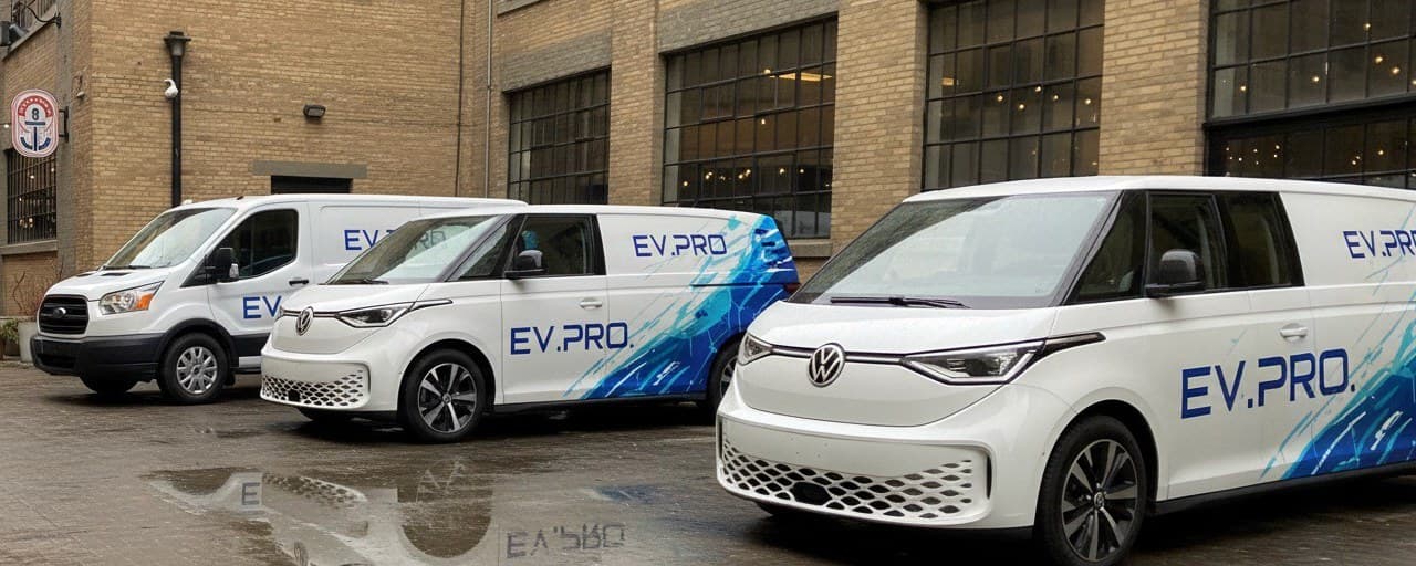 Three EV.PRO branded electric vans parked in a courtyard